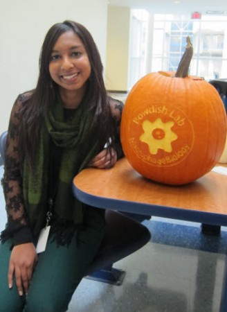 Aveshni Naidoo, MSc sits beside the coolest jack-o'-lantern ever.